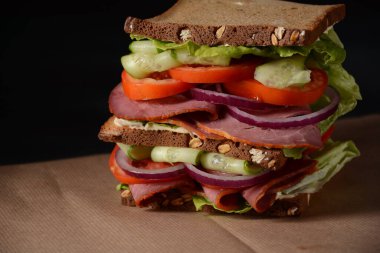 Füme biftekli sandviç, kırmızı soğan, salatalık, domates, marul ve tam tahıllı ekmek. Etli lezzetli, sağlıklı öğle yemeği.