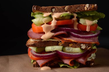 Füme biftekli sandviç, kırmızı soğan, salatalık, domates, marul ve tam tahıllı ekmek. Etli lezzetli, sağlıklı öğle yemeği.