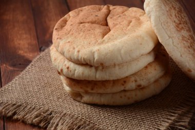 Bir yığın pide ekmeği. Tahta üzerinde Pita ekmeği, Arap ekmeği, yumuşak pişmiş ekmek. Popüler İsrail yemekleri