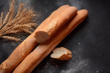 Koyu arkaplan ve buğdaylı Fransız taze ekmeği.