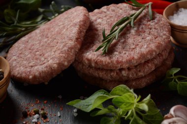 Çiğ etli hamburger köfteleri, baharatlı ve otlu. Beton zeminde hamburgerler.