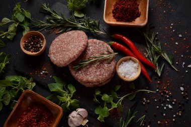 Çiğ etli hamburger köfteleri, baharatlı ve otlu. Beton zeminde hamburgerler.