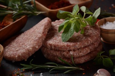 Çiğ etli hamburger köfteleri, baharatlı ve otlu. Beton zeminde hamburgerler.