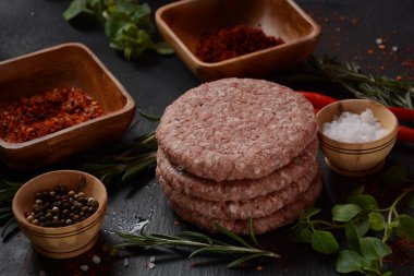 Çiğ etli hamburger köfteleri, baharatlı ve otlu. Beton zeminde hamburgerler.