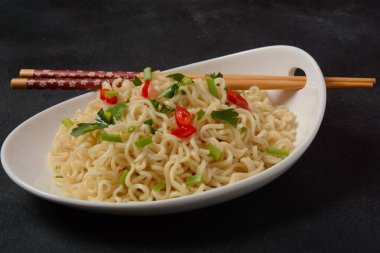 Siyah arka planda çubuklar olan bir kase hazır erişte..