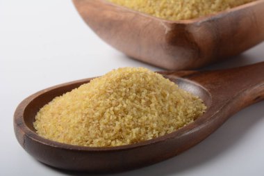 Beyaz masa arkasında ahşap kasede pişmemiş bulgur, köy usulü. Bulgur buğdayları