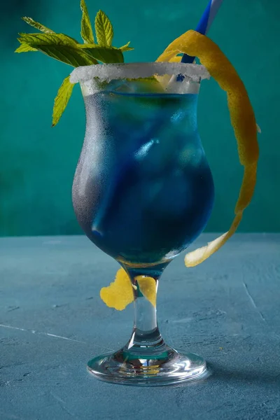 ブルーカラカオリキュール ウォッカ レモン汁とソーダのブルーラグーンカクテル レモンスライスとミントの葉で飾られています — ストック写真