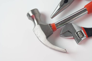 Beyaz arka planda çekiç, pense ve ayarlanabilir İngiliz anahtarı. Standart pençe çekiç ve iğne burun pensesi ve ayarlanabilir anahtarın resmini kapat