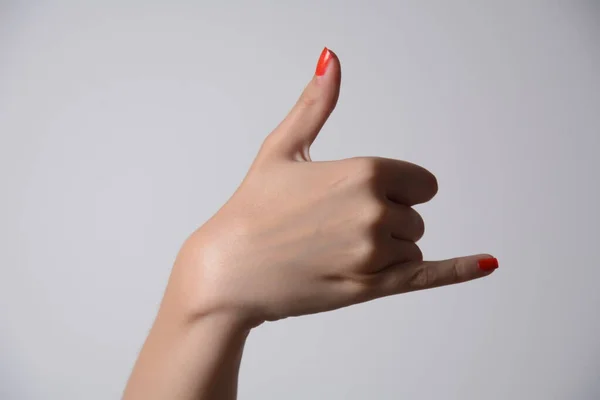Woman's hand shows a sign to make a phone call. Close up. High resolution product.