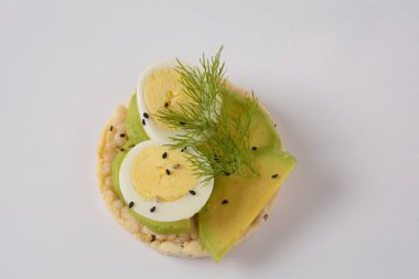 Pirinç ekmeği çıtır çıtır, avokado, haşlanmış yumurta dilimleri ve taze dereotu.