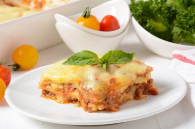 Ev yapımı lezzetli et lazanyası, üstünde fesleğen yaprağı var. Gri arka planda Bachamel soslu İtalyan lazanyası. Peynirli sıcak lazanya.