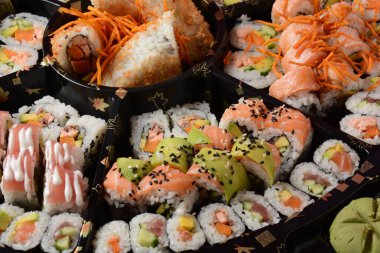 Set of sushi rolls  on a black plastic platter decorated with soy sauce and spices. Ready for delivery