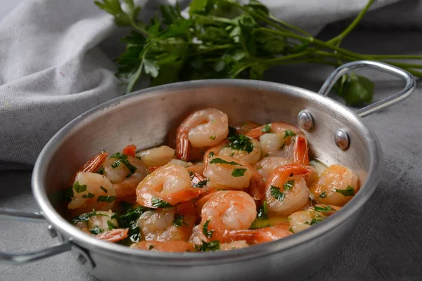 Shrimp scampi with garlic and butter sauce sprinkled with parsley, on a skillet. Keto diet dish