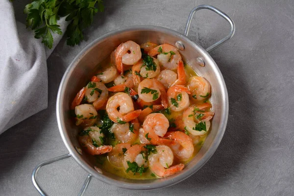 Shrimp scampi with garlic and butter sauce sprinkled with parsley, on a skillet. Keto diet dish