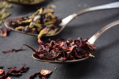 Çayın çeşitli çeşitleri bancha yeşili, Hibiscus, Kelebek Bezelye çiçeği çayı kaşıklar halinde masada