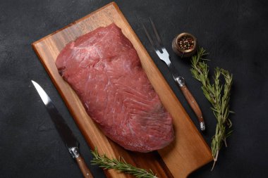 Çiğ et. Biberiyeli sığır filetosu koyu arkaplanda pişirmeye hazır.