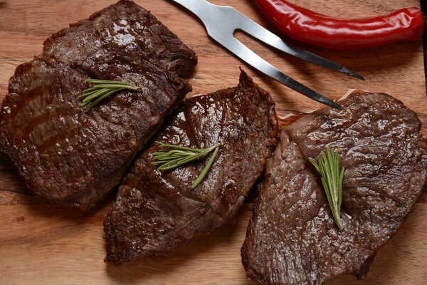 Grilled juicy beef steak with rosemary, fried meat, close-up. Top Blade steaks on wooden board