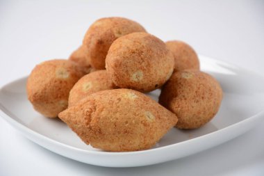 Deep fried kibbeh of ground beef meat mixed with bulgur, stuffed with fried minced meat with pine nuts on a clay plate on white plate