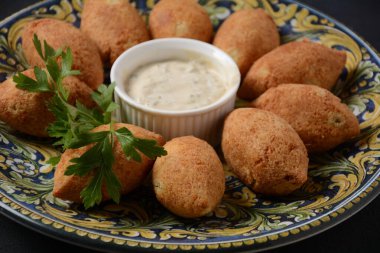 Deep fried kibbeh of ground beef meat mixed with bulgur, stuffed with fried minced meat with pine nuts on a clay plate on dark background