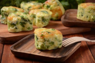 Sağlıklı atıştırmalık Brokoli çörekleri, çedar peyniri ve ahşap masanın üzerindeki kesim tahtasına yakın plan kekik.