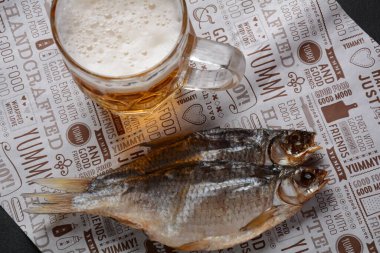Tuzlu kurutulmuş balık hamamböceği ve hafif köpüklü bira bardağı..