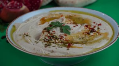 Bir kase zeytinyağı, biber ve limonlu humusa bir parça pita ekmeği batırmak.