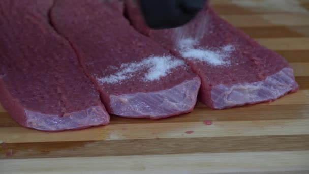 Händerna Med Svarta Gummihandskar Applicerar Försiktigt Salt Råa Köttskivorna — Stockvideo