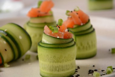 Salatalık ruloları tuzlu somon parçaları, siyah beyaz susam tohumu, doğranmış yeşil soğan. Tatil sebze aperatifleri.