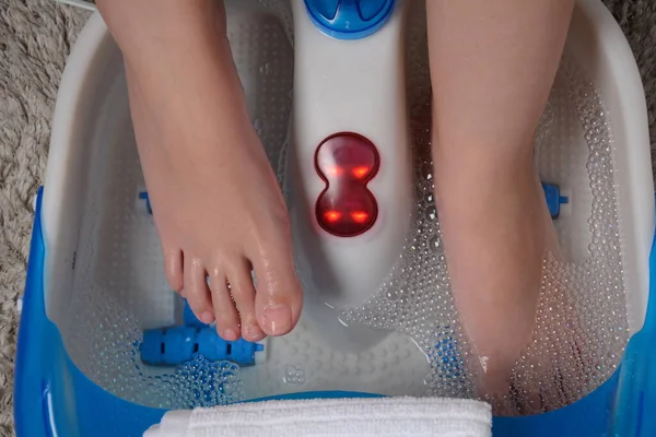 Female feet in a vibrating foot massager. Electric massage foot bath. Relax after work. Pedicure and foot care