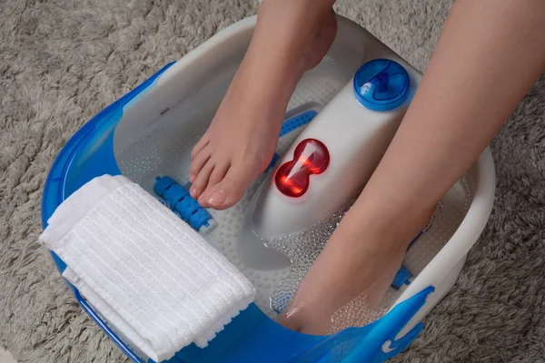 Titreşen ayak masajcısının içindeki kadın ayakları. Elektrikli masaj ayak banyosu. İşten sonra rahatla. Pedikür ve ayak bakımı