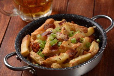 Eritilmiş Çedar peynirli patates kızartması ve çıtır pastırma. Peynirli, pastırmalı ve soğanlı poutine.