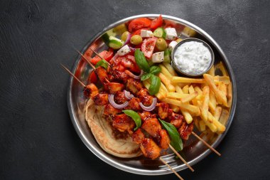 Kızarmış souvlaki, Yunan salatası ve ahşap masada tzatziki. Tavuk şişleri souvlaki, pide ekmeği - koyu arkaplanda Yunan usulü lezzetli bir öğle yemeği