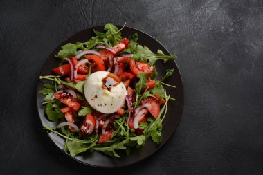Domatesli salata ve fesleğenli Burrata peyniri ve koyu arkaplanda zeytinyağı. Geleneksel İtalyan burrata peyniri. Domates ve roka ile servis edilen Burrata.