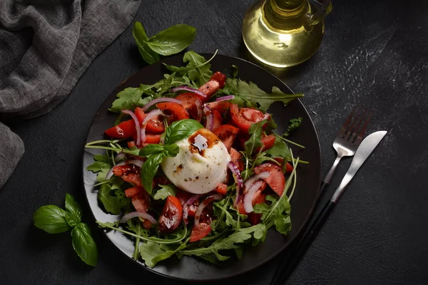 Domatesli salata ve fesleğenli Burrata peyniri ve koyu arkaplanda zeytinyağı. Geleneksel İtalyan burrata peyniri. Domates ve roka ile servis edilen Burrata.
