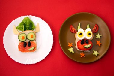 2021 boğa ineğinin yenilebilir sembolü olan iki komik sandviç tost ekmeği, balık, peynir, kuru üzüm ve sebzeden yapılır. Çocuklar için kahvaltı fikri. Noel yemeği üst görünümü. yemek sanatı