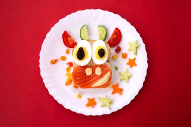 Kızarmış ekmek, kırmızı balık, peynir, kuru üzüm, yumurta ve sebzeden yapılmış yenilebilir 2021 boğa ineği sembollü komik sandviç. Çocuklar için kahvaltı fikri. Noel yemeği üst görünümü. yemek sanatı