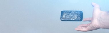 Gri arka planda kırık ekranlı cep telefonu. Kopyalama alanı olan pankart