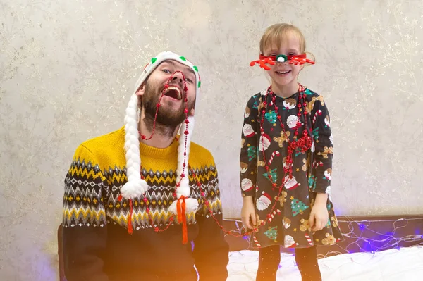 鹿の角の赤いサンタクロースの帽子と子供の女の子を身に着けている男は 楽しみ クリスマス休暇とお祝いの準備をしています 娘と一緒に父 家族のお祝いの概念を居心地の良い — ストック写真