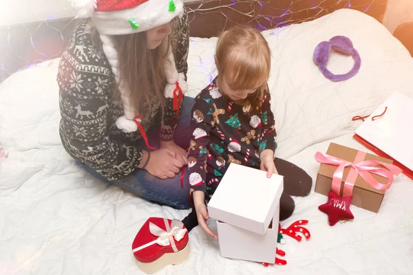 Mulher e criança menina embalagem presentes de Natal para amigos e familiares. mãe vestindo chapéu vermelho Papai Noel com criança em chifres de veado se divertir, brincar, preparação para feriados de Natal e celebração. — Fotografia de Stock