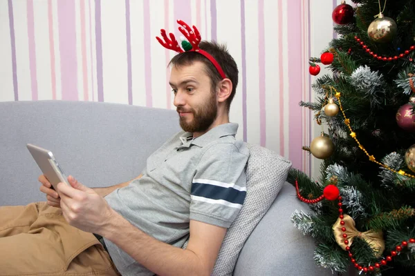 クリスマスオンラインおめでとうございます ビデオ通話の友人や両親のためにタブレットを使用してクリスマスツリーの近くに笑顔男 クリスマスオンラインショッピング — ストック写真