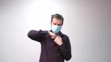 Tıbbi maske takan, kırmızı kalp takan ve dans eden güzel bir adamın portresi. İnternette sevgililer gününü kutlayan adamdan tebrikler. Romantik.