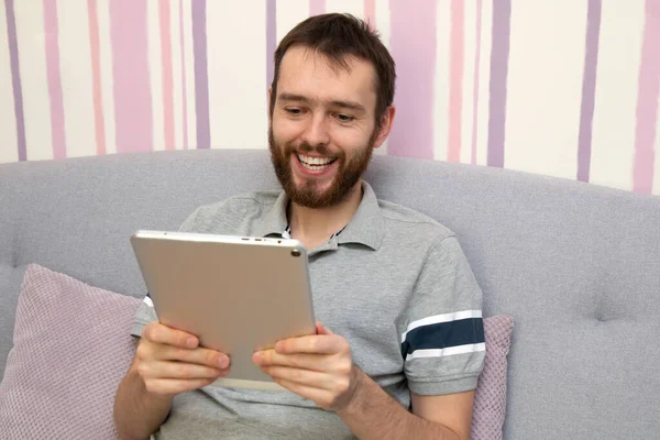 Atractivo Joven Con Barba Está Utilizando Una Tableta Sonriendo Sofá —  Fotos de Stock