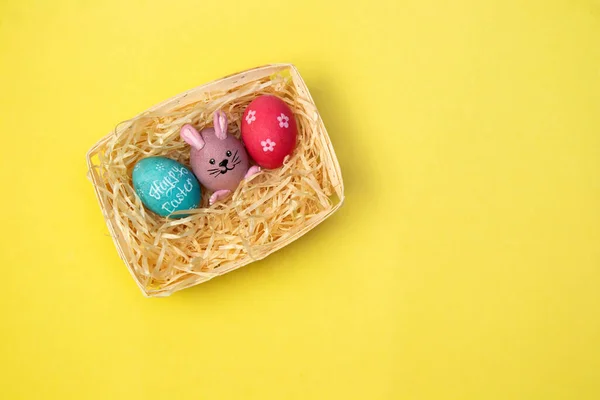 Pintura Ovos Páscoa Coloridos Uma Cesta Fundo Amarelo Visão Superior — Fotografia de Stock