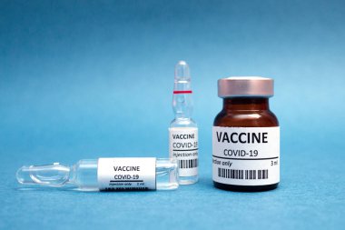 Korona virüsü enfeksiyonunun önlenmesi, aşılanması ve tedavisi için mavi zemin üzerinde aşı ve şırıngalar var. Genel aşı ve Sağlık Hizmetleri Tıbbi Konsepti