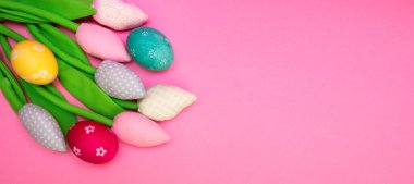 Paskalya arkaplanı boyalı yumurtalar ve renkli lalelerle dolu. Kopyalama alanı olan üst görünüm. Düz pankart