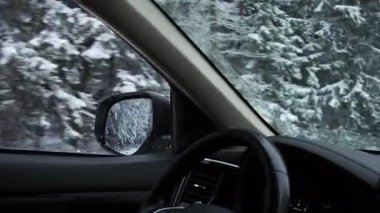 Kış karlı ormanlarda karla kaplı yolda giden araba. Dikiz aynasından bak.