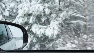 Kış karlı ormanlarda karla kaplı yolda giden araba. Dikiz aynasından bak.