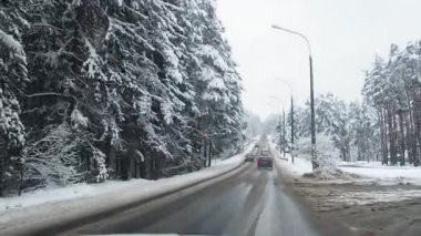Kış karlı ormanlarda karla kaplı yolda giden araba. Pencereden görüntüle