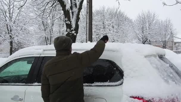 El hombre limpia su coche con cepillo de la nieve. Persona cepillando nieve fresca del coche en el invierno — Vídeo de stock