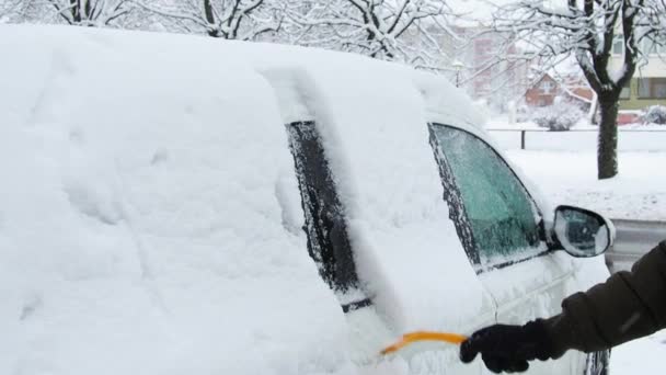 El hombre limpia su coche con cepillo de la nieve. Persona cepillando nieve fresca del coche en el invierno — Vídeo de stock